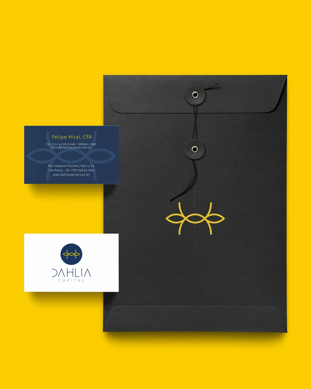 Cartões de visita e envelope da Dahlia Capital, fundo amarelo, símbolo em relevo no envelope preto