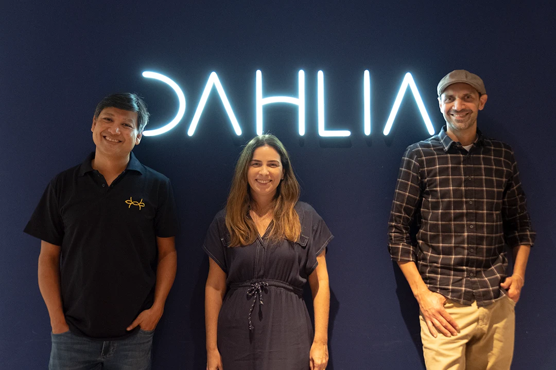 Cris com dois dos fundadores da Dahlia Capital, em frente ao letreiro de neon do logo