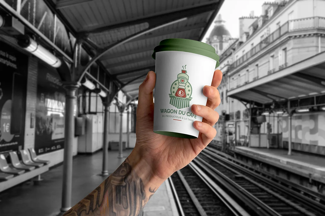 Gobelet Wagon du Café tenu à la main sur un quai de gare